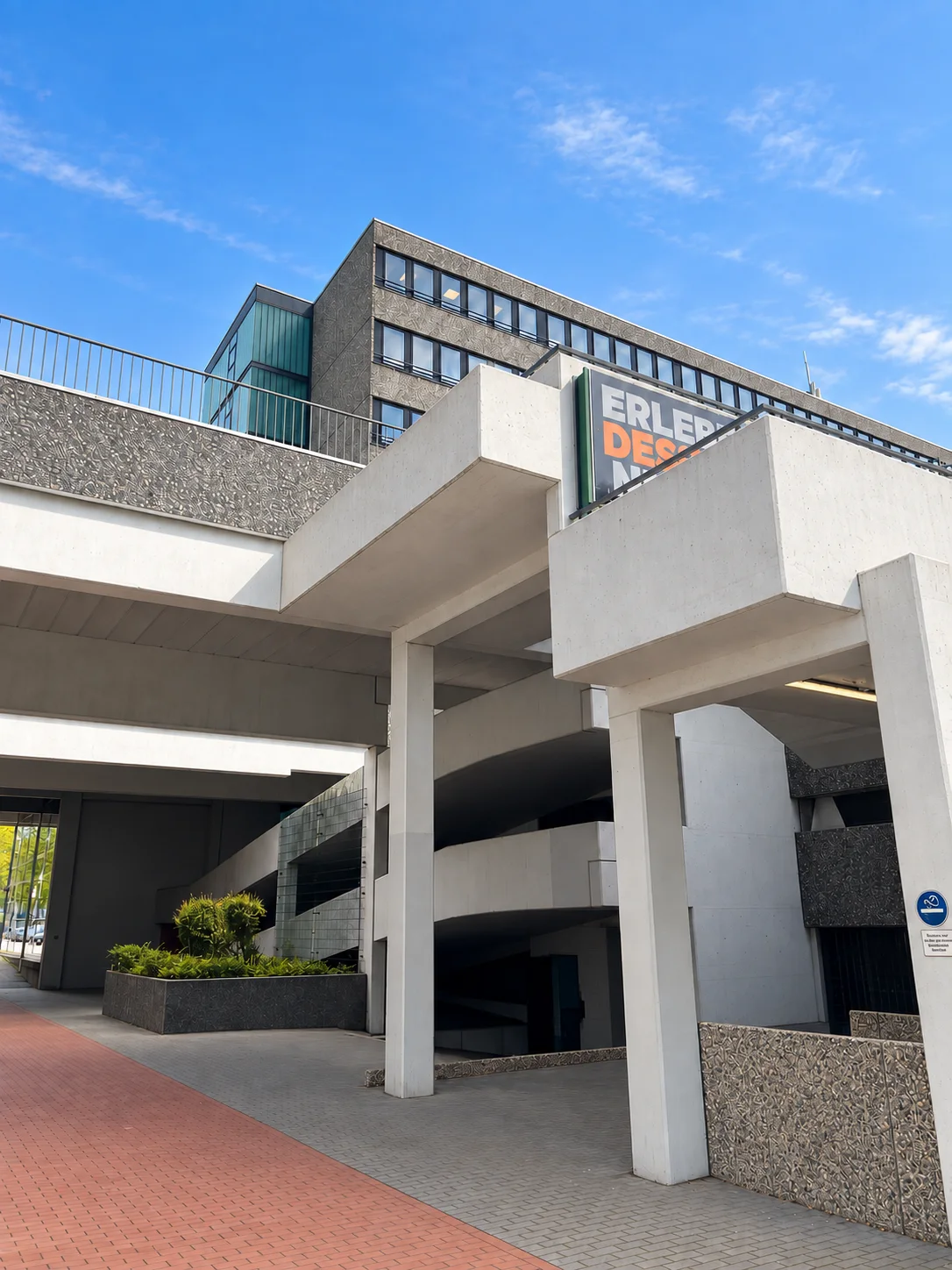 Sculptural concrete walkways and columns beneath the studio building against a blue sky
